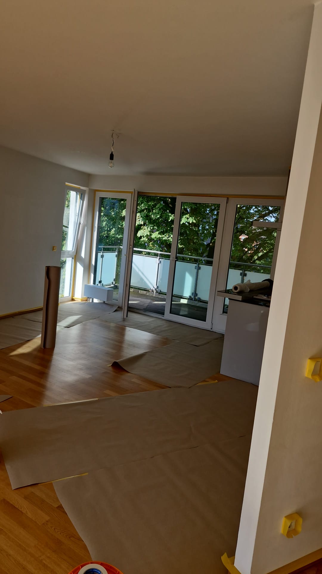 Wohnraum mit großen Fenstern, abgedecktem Boden und mit Klebeband geschützten Bauteilen.