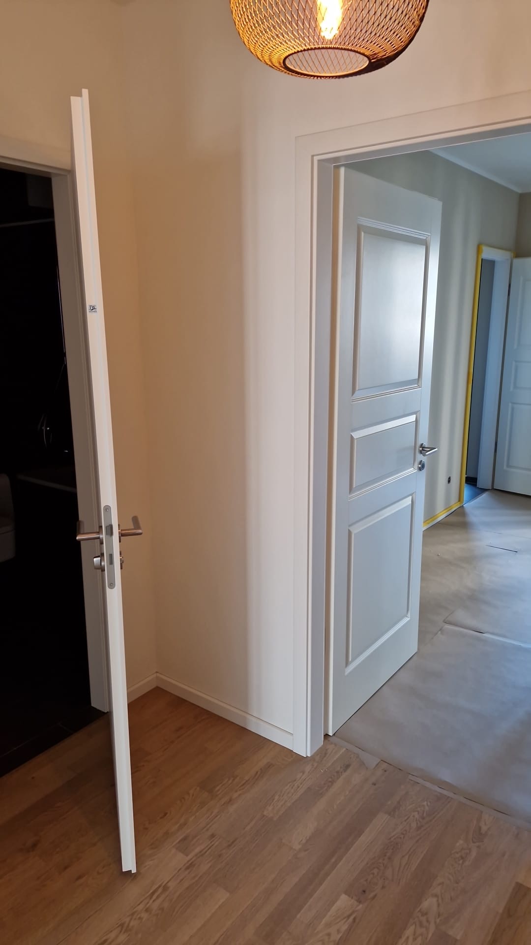 Weiße Kassettentüren und Zargen in einem Flur mit Boden in Holzoptik.