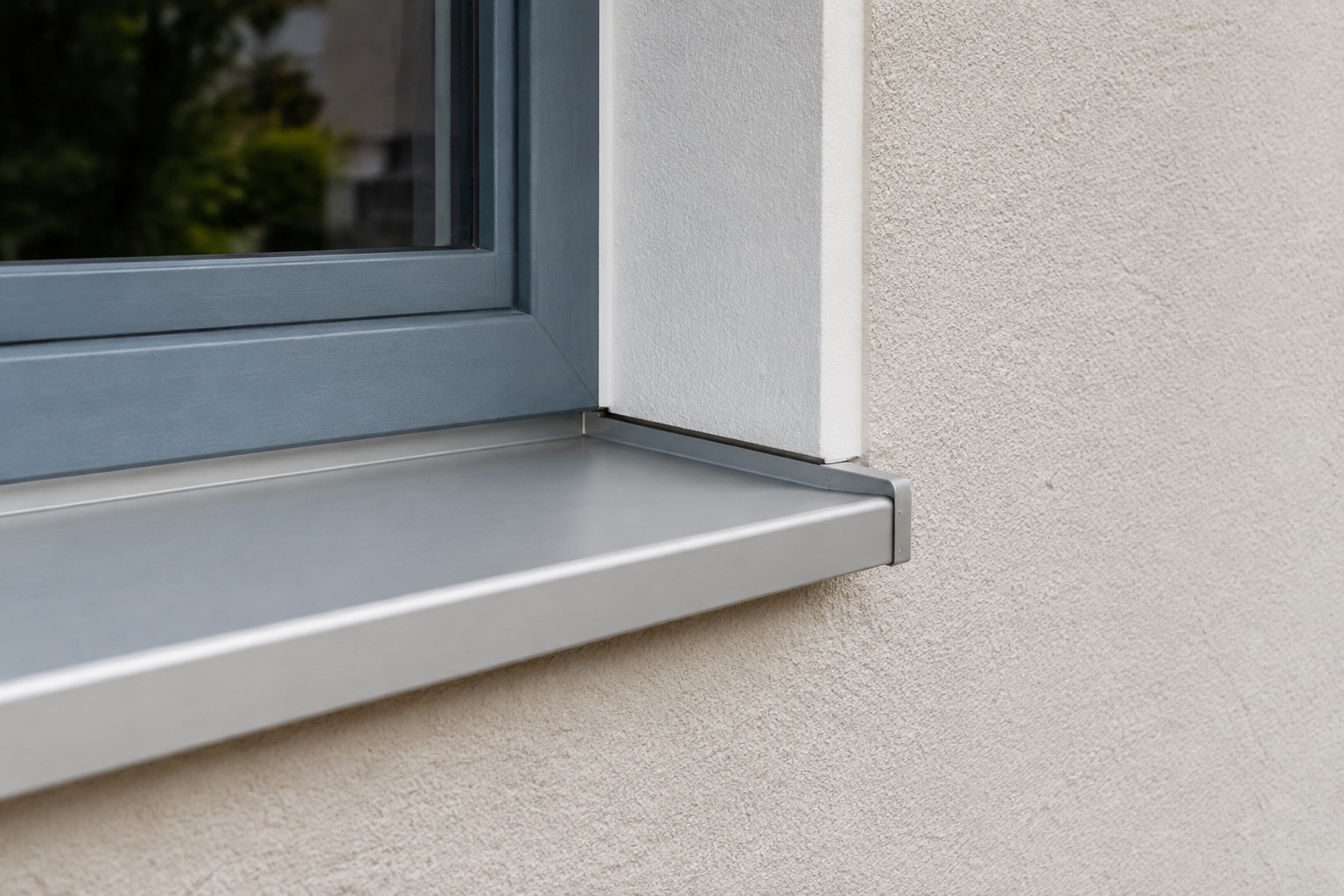 Detail einer hell verputzten Fassade mit sauberer Fensterlaibung und blaugrauem Fensterrahmen.